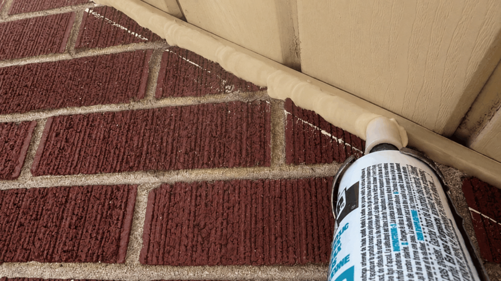 Beige caulking sealing a soffit and brick gap to prevent bats from entering a home