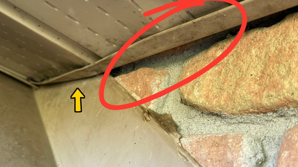 Gap between soffit and brick wall with staining around a common bat entry point.