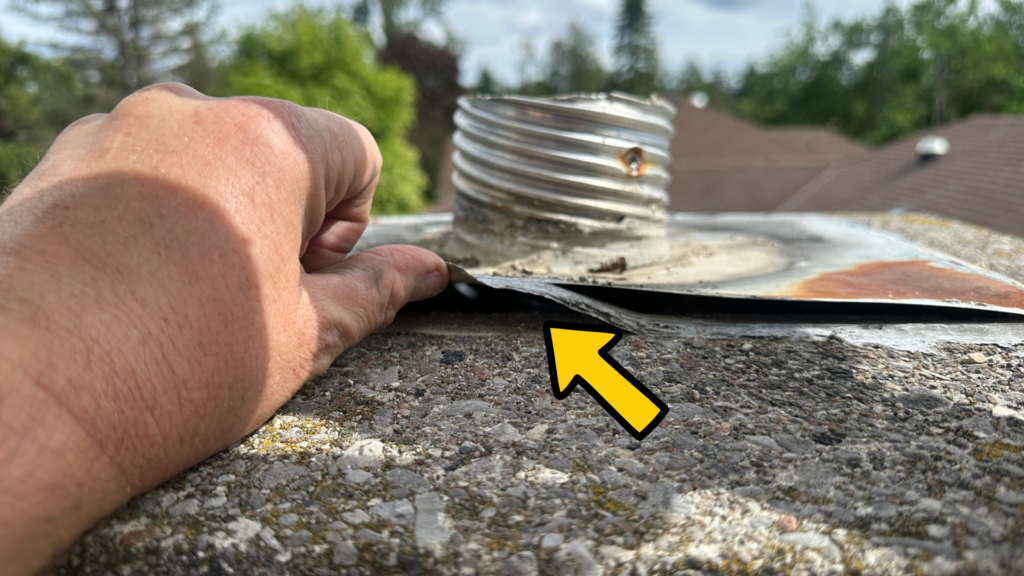 Hand lifting loose chimney-top flashing with a visible gap underneath